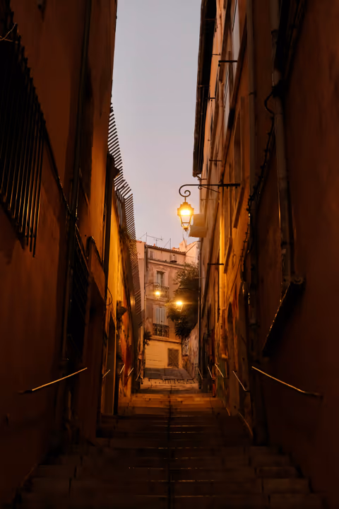 narrow cobblestone street with gas lamps at dusk