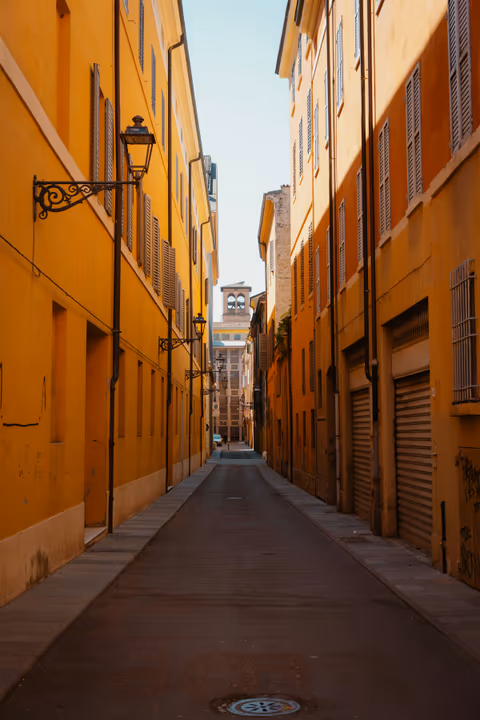 narrow street with yellow buildings and a bell tower