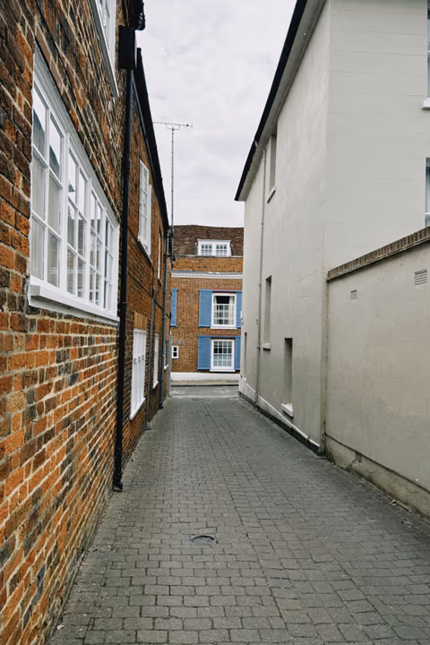 cobblestone alleyway between brick and white walls