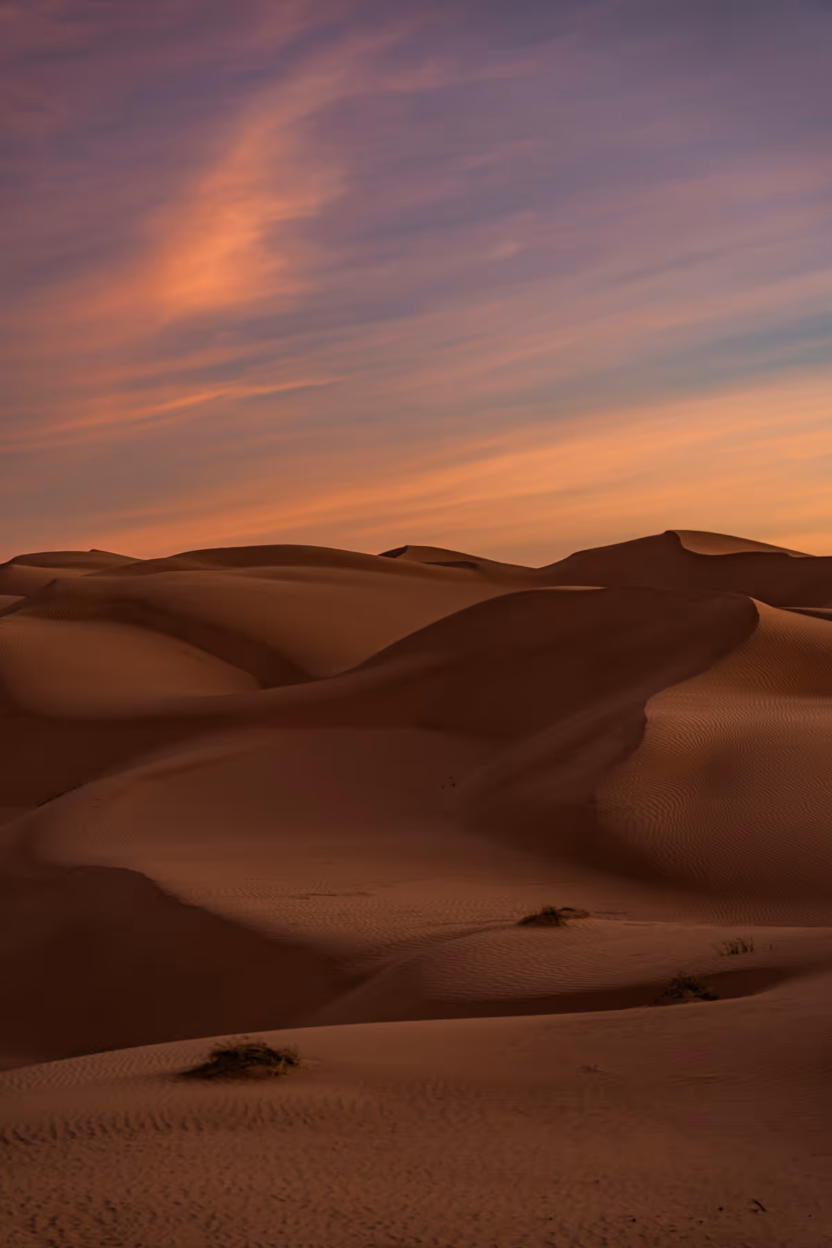 a sunset in the desert with sand dunes