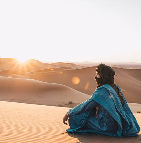 woman sitting on sand during sunset