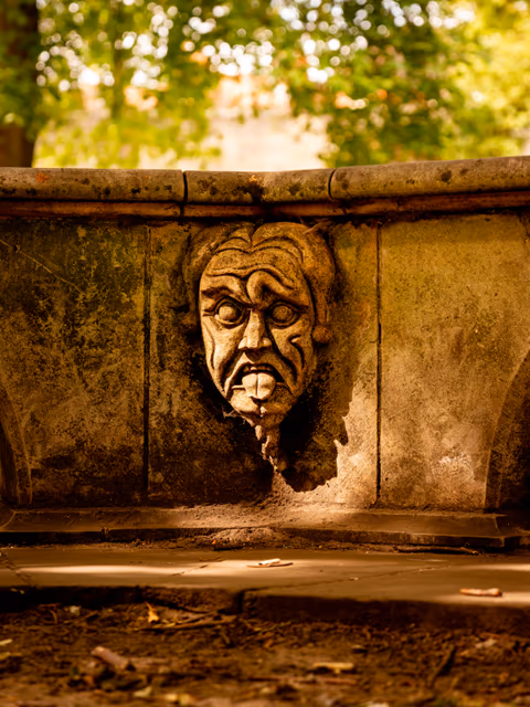 stone gargoyle face on an old fountain