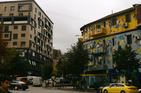 a yellow car next to tall buildings